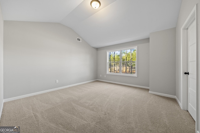 unfurnished bedroom featuring light colored carpet and lofted ceiling