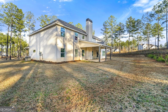 rear view of property with cooling unit, a lawn, and a patio