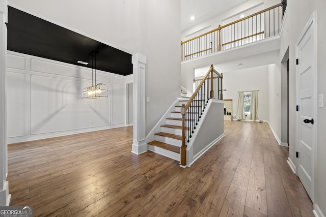 foyer with a high ceiling, wood-type flooring, and an inviting chandelier