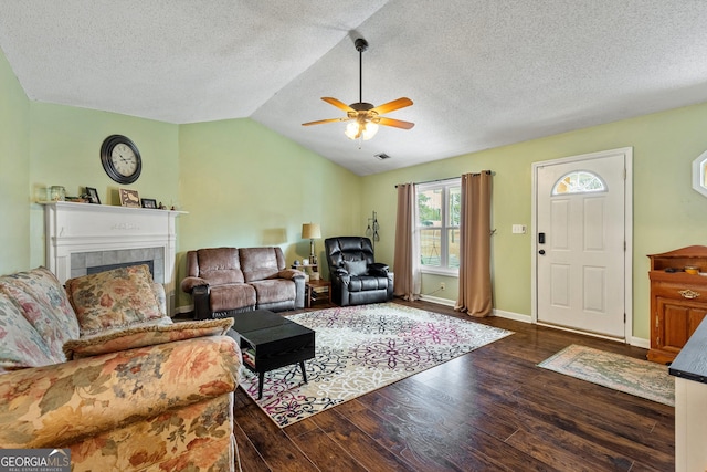 living room featuring vaulted ceiling, dark hardwood / wood-style floors, a fireplace, ceiling fan, and a textured ceiling