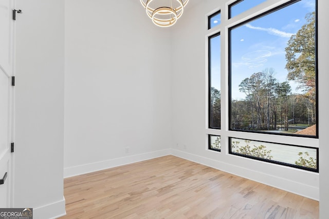 unfurnished room featuring an inviting chandelier and light hardwood / wood-style floors