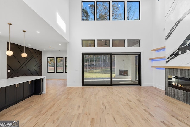 unfurnished living room featuring light hardwood / wood-style floors and a high ceiling