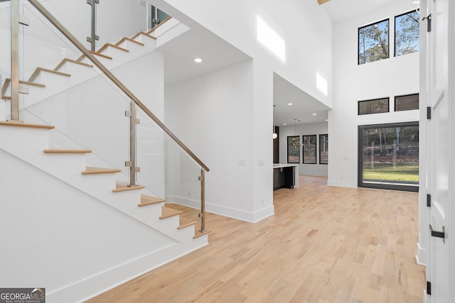 entrance foyer featuring a towering ceiling and light hardwood / wood-style floors