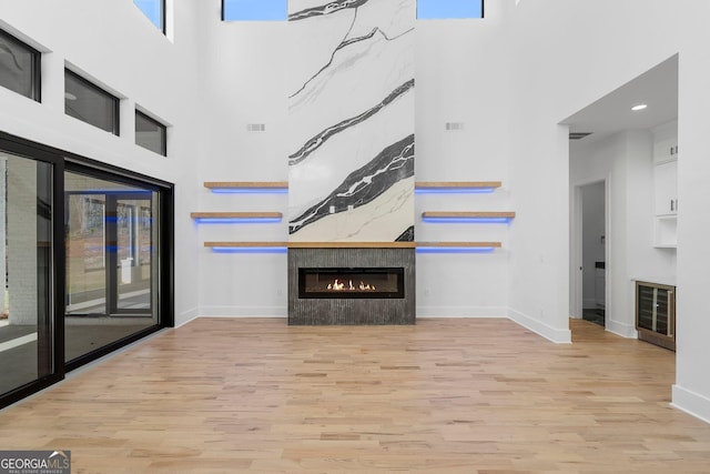 unfurnished living room with a high ceiling, light wood-type flooring, and a fireplace