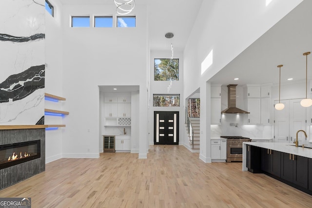 unfurnished living room featuring sink, a high ceiling, and light wood-type flooring