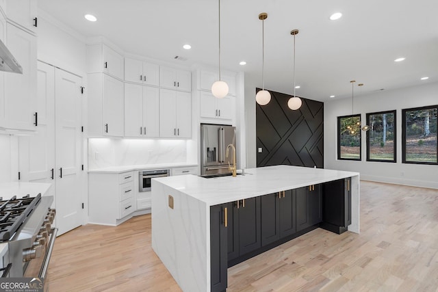 kitchen featuring sink, white cabinetry, decorative light fixtures, a large island with sink, and appliances with stainless steel finishes