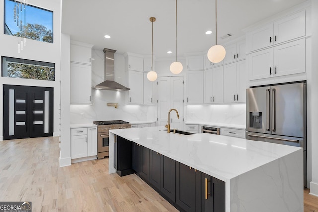 kitchen featuring a large island, white cabinets, premium appliances, and wall chimney exhaust hood