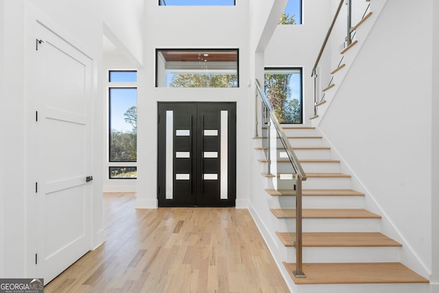 entryway with a towering ceiling and light wood-type flooring