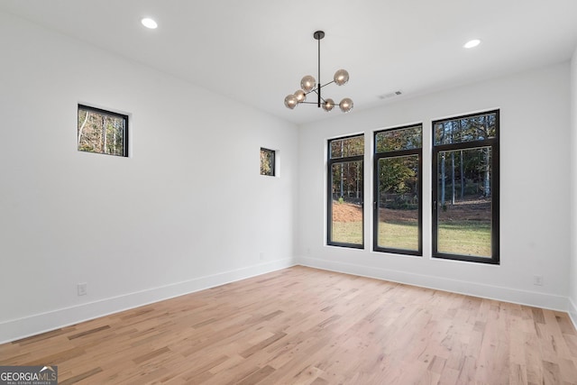 spare room with a notable chandelier and light hardwood / wood-style flooring