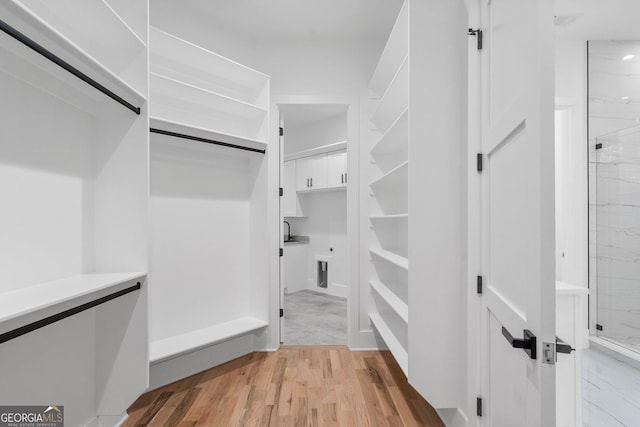 spacious closet featuring a barn door, sink, and light wood-type flooring