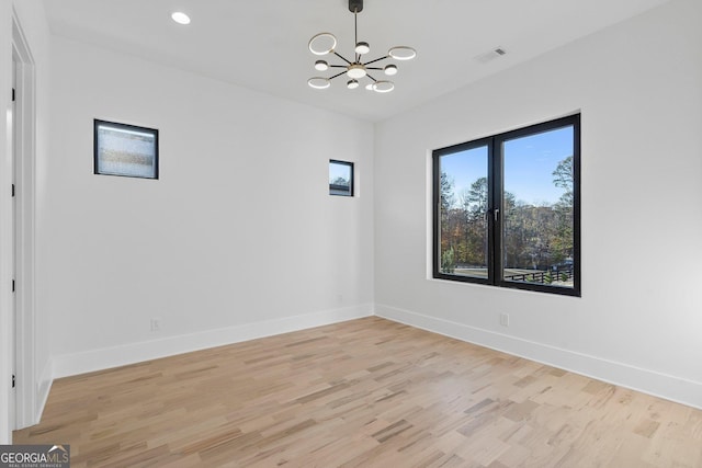 empty room with light hardwood / wood-style floors and a chandelier