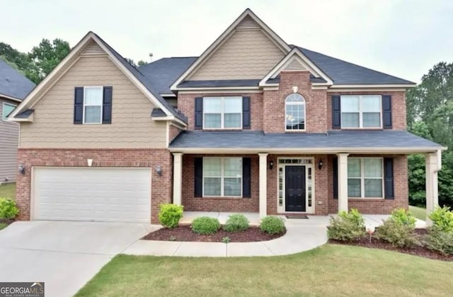 craftsman-style house featuring a front yard, concrete driveway, brick siding, and an attached garage