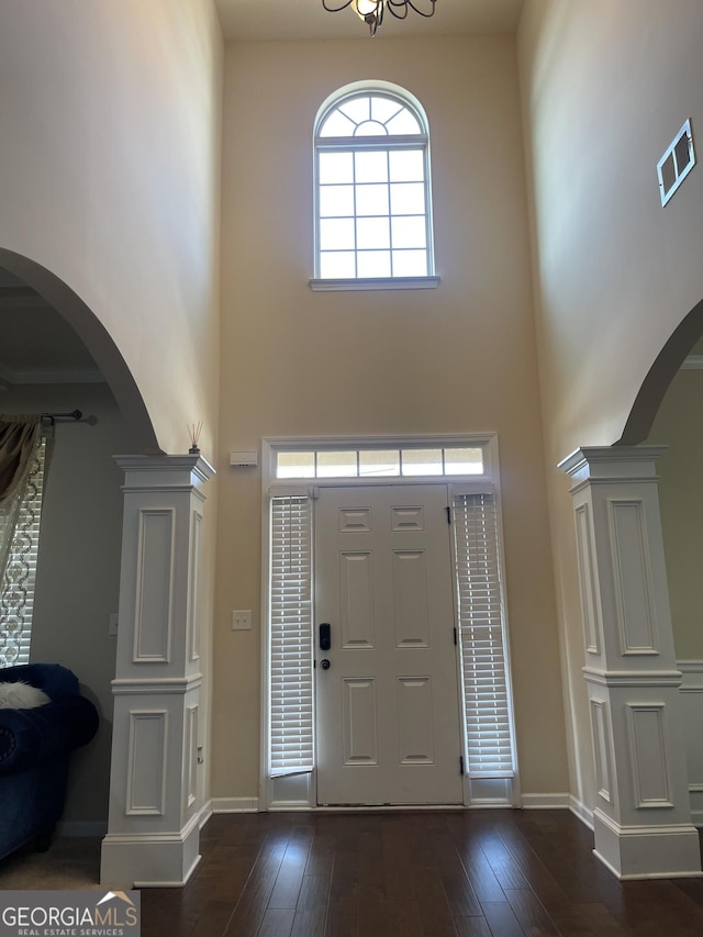 entrance foyer with arched walkways, a high ceiling, visible vents, baseboards, and dark wood-style floors