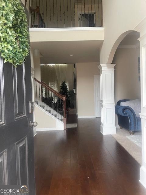 entrance foyer featuring crown molding, a towering ceiling, decorative columns, and dark hardwood / wood-style floors