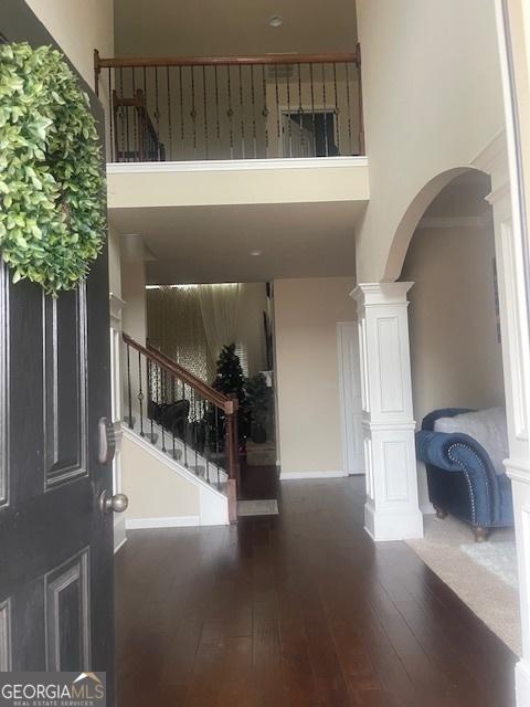 entrance foyer featuring dark hardwood / wood-style floors, decorative columns, and a high ceiling