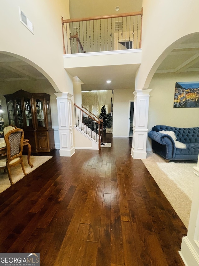 foyer entrance with visible vents, stairway, hardwood / wood-style flooring, and a towering ceiling