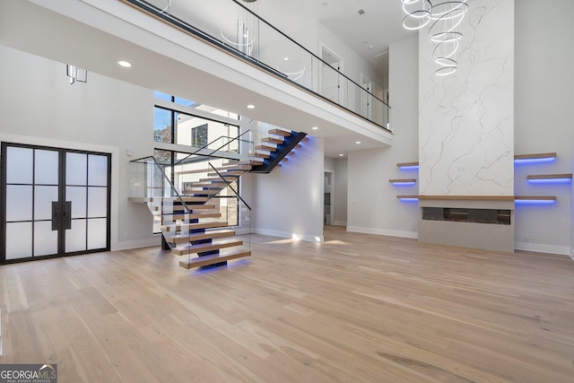 staircase featuring hardwood / wood-style flooring, a high end fireplace, and a high ceiling