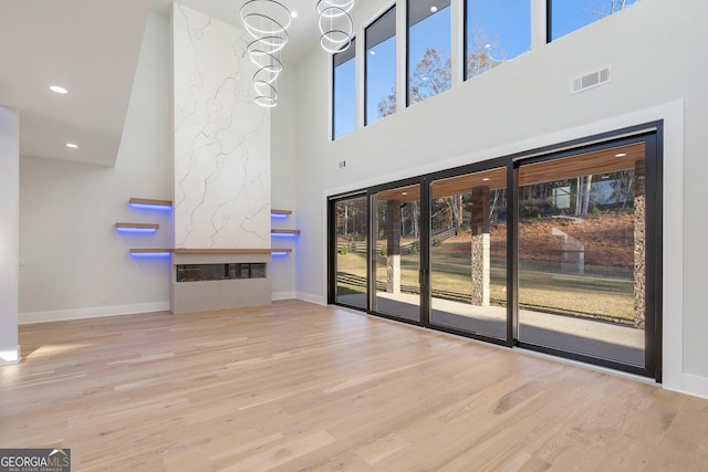 unfurnished living room with a premium fireplace, plenty of natural light, and light hardwood / wood-style flooring