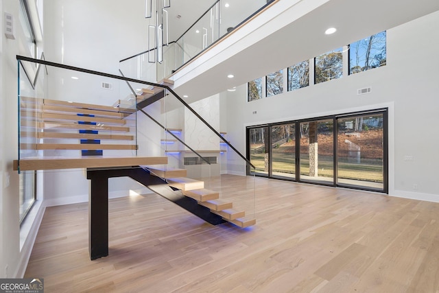 staircase featuring a towering ceiling and wood-type flooring