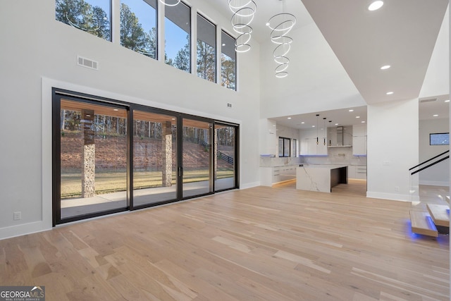 unfurnished living room with a notable chandelier and light hardwood / wood-style floors