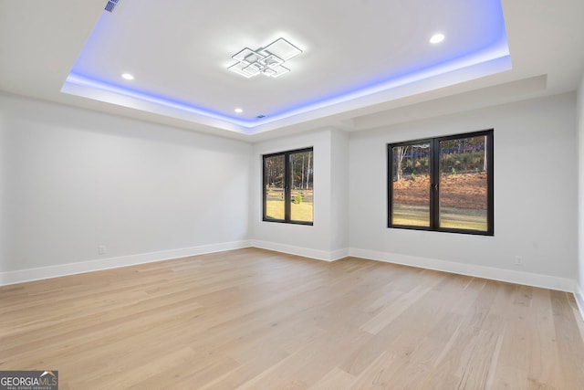 empty room featuring light hardwood / wood-style flooring and a tray ceiling