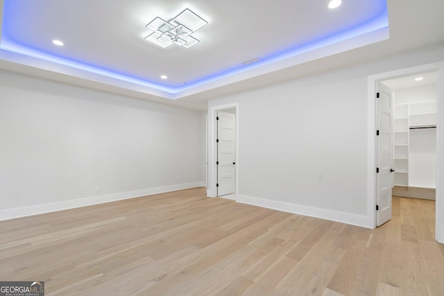 unfurnished room featuring a tray ceiling and light wood-type flooring