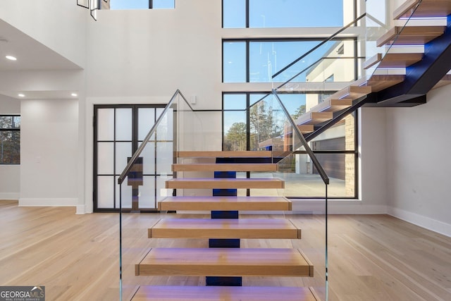 stairs with hardwood / wood-style flooring and a towering ceiling