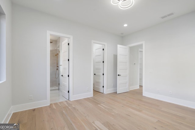 unfurnished bedroom featuring a walk in closet, connected bathroom, and light wood-type flooring