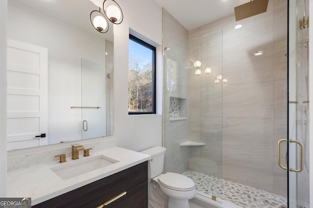 bathroom featuring vanity, a shower with shower door, and toilet