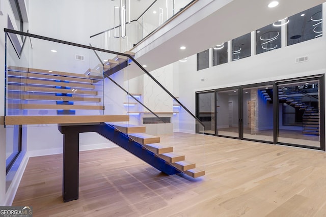 staircase with hardwood / wood-style floors and a high ceiling