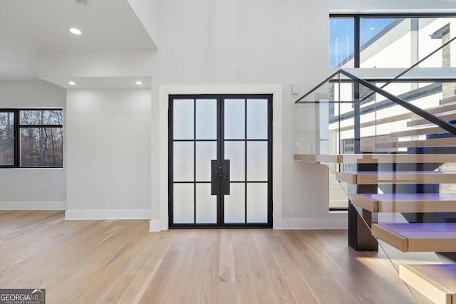 entryway with plenty of natural light, french doors, and light wood-type flooring