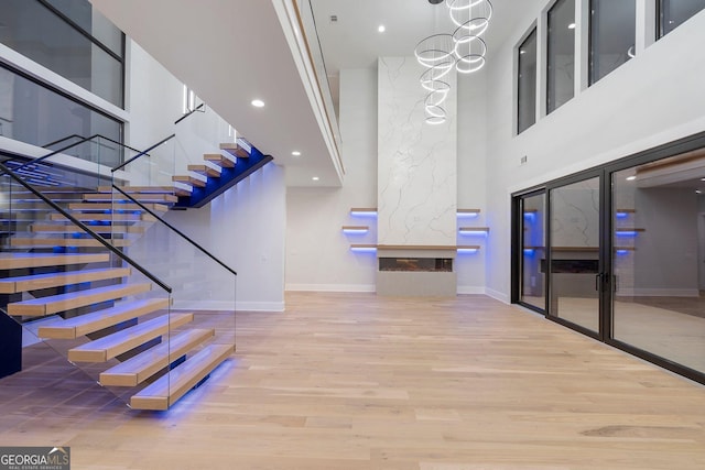 staircase featuring an inviting chandelier, wood-type flooring, and a high ceiling