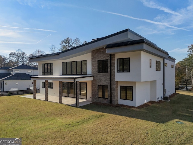 back of property with central AC unit, a patio, and a lawn