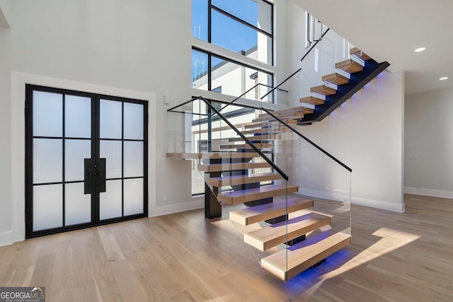 staircase featuring hardwood / wood-style floors and a high ceiling