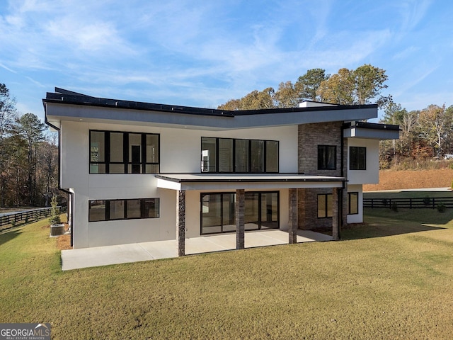 rear view of house featuring a lawn and a patio