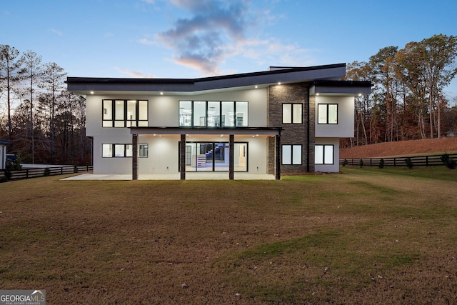 back house at dusk featuring a yard and a patio area