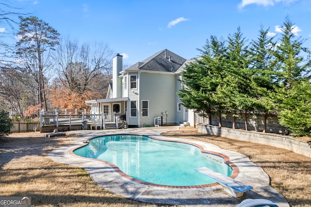 view of swimming pool with a wooden deck and a diving board