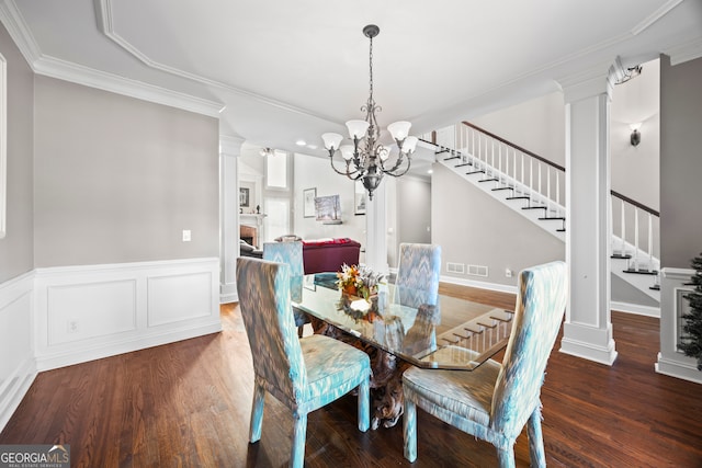 dining room with dark wood-type flooring, ornamental molding, a chandelier, and ornate columns