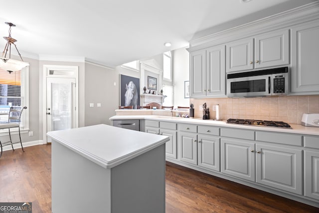 kitchen with backsplash, stainless steel appliances, a center island, ornamental molding, and decorative light fixtures