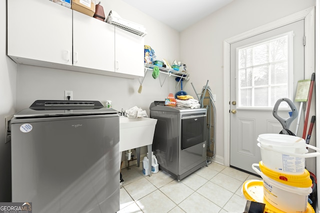 laundry room featuring cabinets, washing machine and dryer, and light tile patterned floors