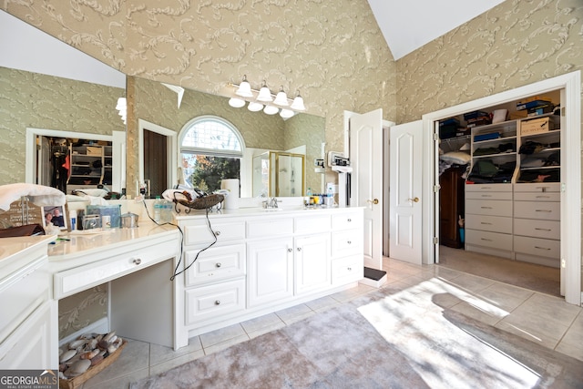 bathroom featuring tile patterned flooring, vanity, vaulted ceiling, and a shower with door