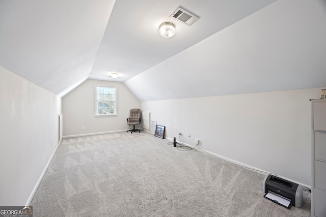 additional living space featuring vaulted ceiling and light colored carpet