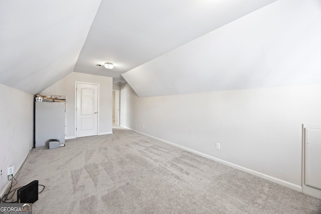 bonus room with lofted ceiling and light carpet