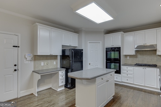 kitchen featuring white cabinets, ornamental molding, a center island, black appliances, and light hardwood / wood-style flooring