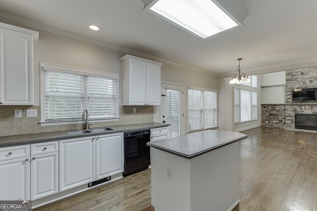 kitchen with a kitchen island, dishwasher, sink, white cabinets, and ornamental molding