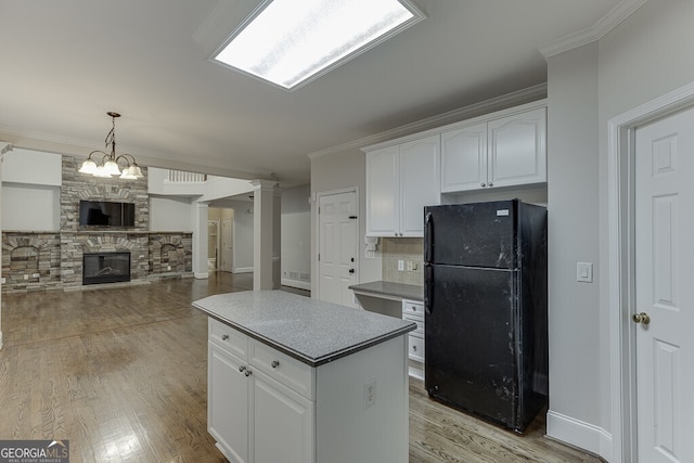 kitchen featuring hanging light fixtures, a kitchen island, black refrigerator, and white cabinets