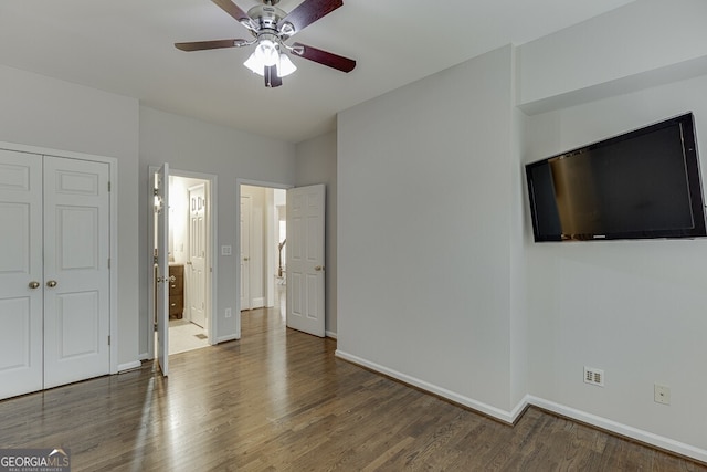 unfurnished bedroom featuring a closet, ensuite bath, dark hardwood / wood-style floors, and ceiling fan