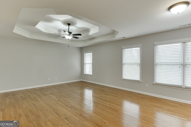 unfurnished room featuring ceiling fan, ornamental molding, a raised ceiling, and light wood-type flooring