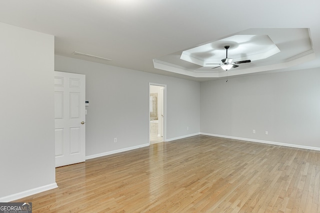 spare room with crown molding, a tray ceiling, light hardwood / wood-style floors, and ceiling fan