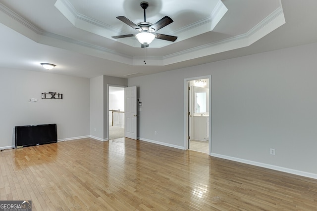 interior space with ornamental molding, ceiling fan, light hardwood / wood-style floors, and a tray ceiling